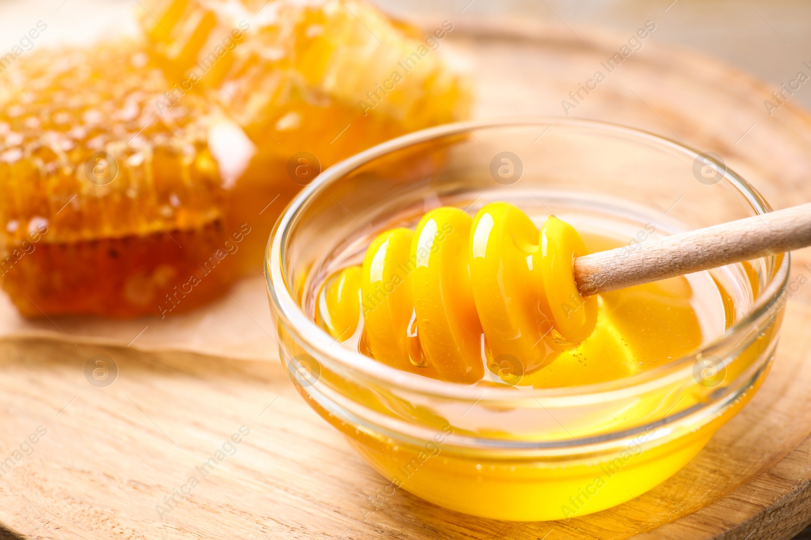 Photo of Tasty aromatic honey in bowl on wooden table