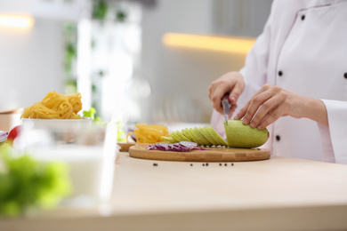 Female chef cooking food at kitchen table, closeup