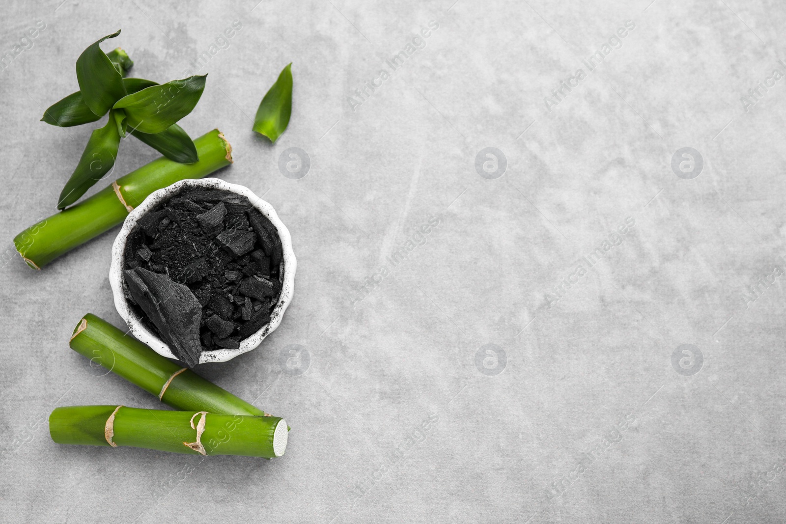 Photo of Fresh bamboo and charcoal on light gray table, flat lay. Space for text