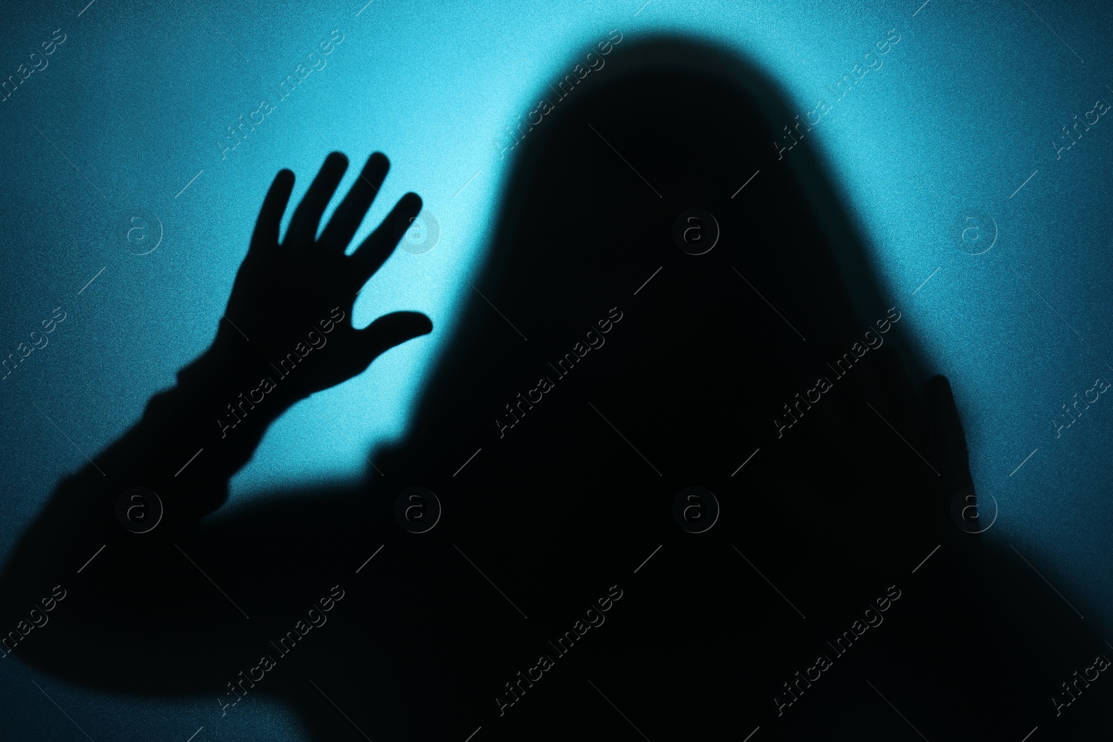 Photo of Silhouette of ghost behind glass against blue background