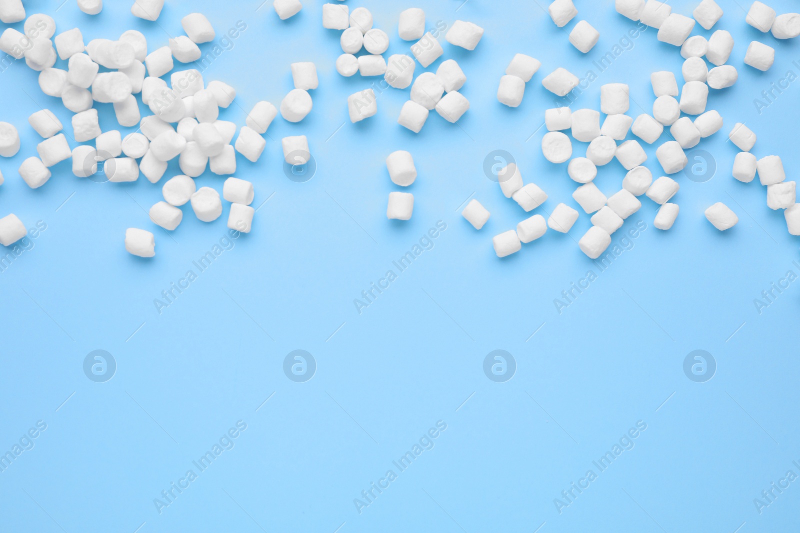 Photo of Delicious marshmallows on light blue background, flat lay. Space for text