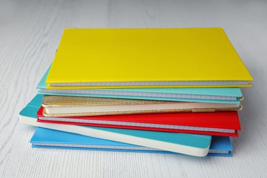Photo of Stack of colorful planners on white wooden table