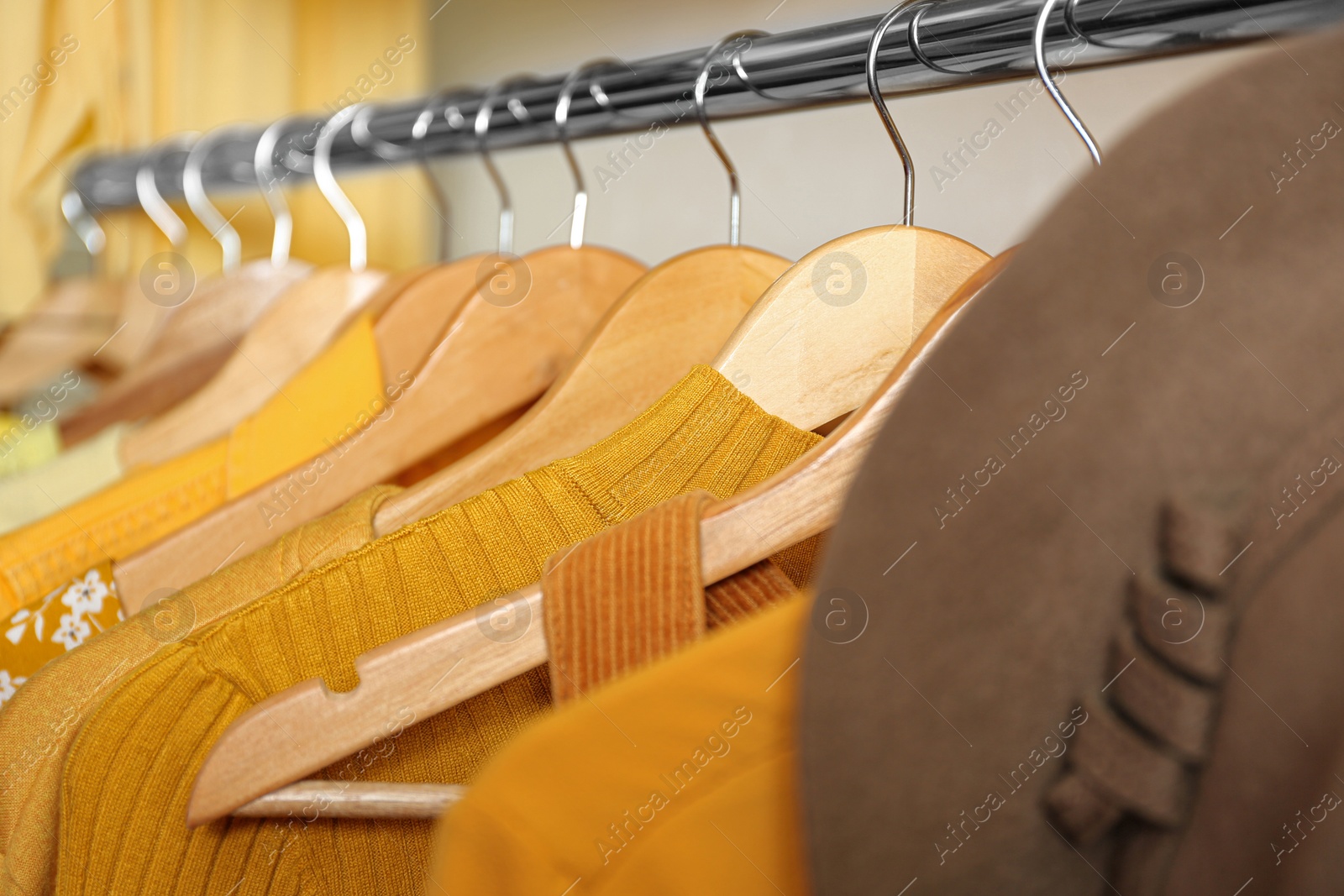 Photo of Different styling clothes on wooden hangers in wardrobe, closeup. Fashion blogger