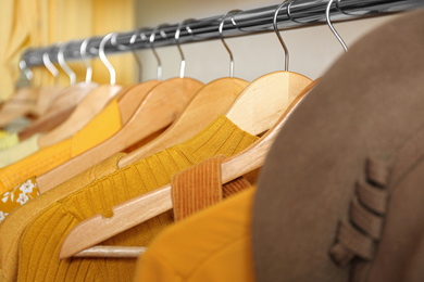 Different styling clothes on wooden hangers in wardrobe, closeup. Fashion blogger