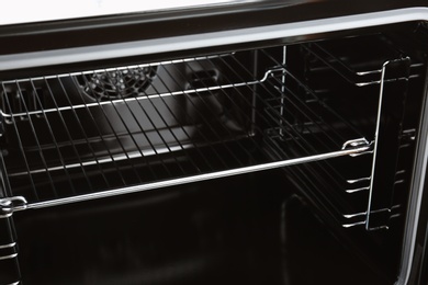 Photo of Open empty electric oven with rack, closeup