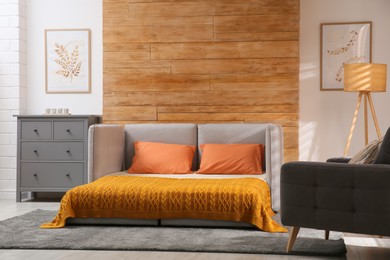 Photo of Room interior with sofa unfolded into bed near wooden wall