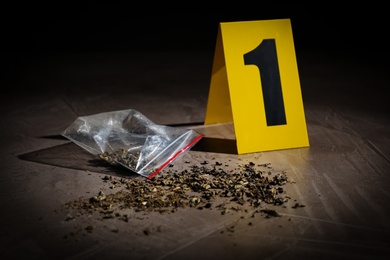 Scattered cannabis and crime scene marker on grey stone table