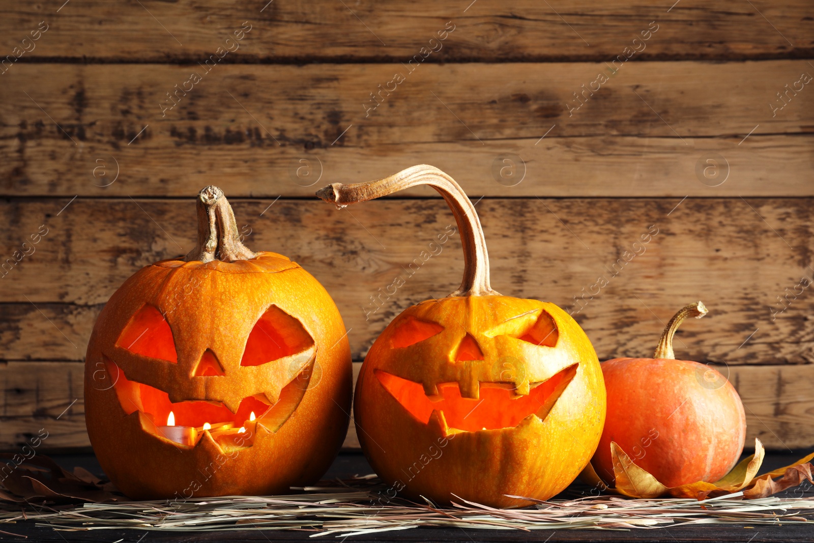 Photo of Halloween pumpkin head jack lanterns on table against wooden background