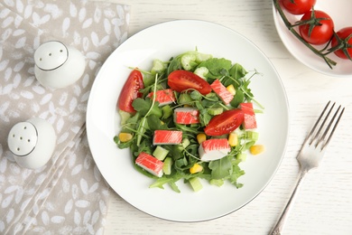 Tasty crab stick salad served on white table, flat lay