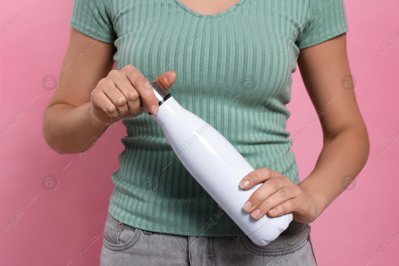 Photo of Woman holding thermo bottle on pink background, closeup