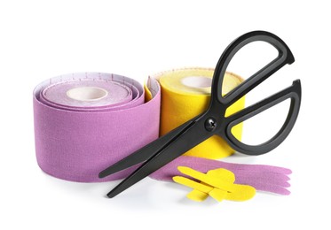 Photo of Scissors, bright kinesio tape rolls and pieces on white background