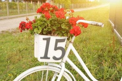 Photo of White bicycle with number 15 on basket of flowers outdoors