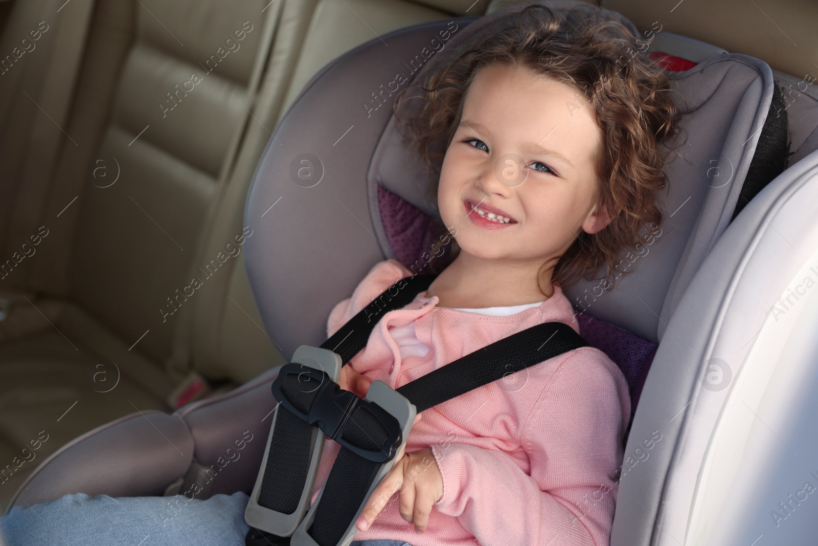 Photo of Cute little girl sitting in child safety seat inside car