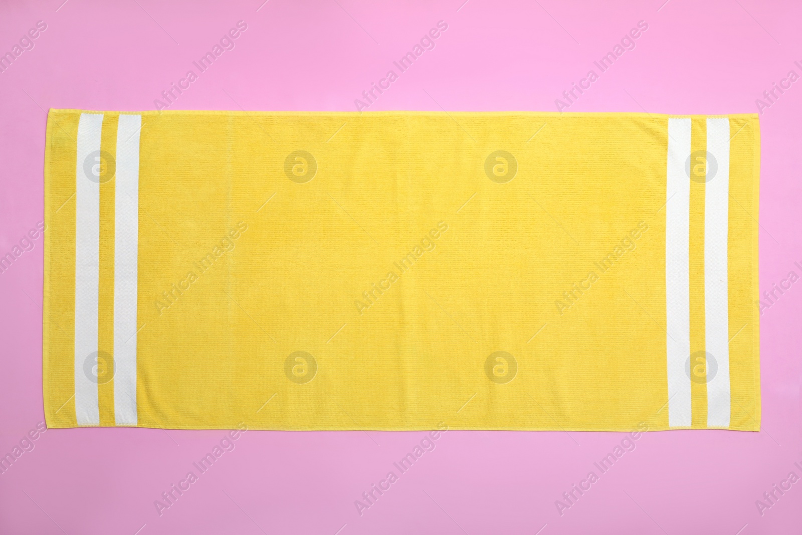 Photo of Yellow beach towel on pink background, top view