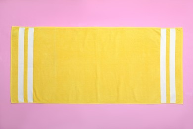 Photo of Yellow beach towel on pink background, top view
