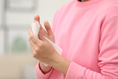 Photo of Woman cleaning hands with paper tissue on blurred background, closeup