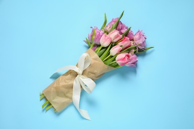 Photo of Beautiful bouquet of colorful tulip flowers on light blue background, top view