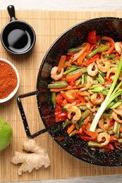 Photo of Shrimp stir fry with vegetables in wok and ingredients on table, flat lay