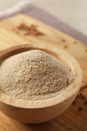 Photo of Bowl of buckwheat flour on wooden board, closeup