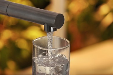 Photo of Filling glass with tap water from faucet on blurred background, closeup. Space for text