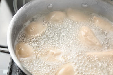 Photo of Closeup of metal stewpan with boiling water and dumplings. Home cooking