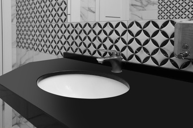 Stylish black counter with sink in public toilet