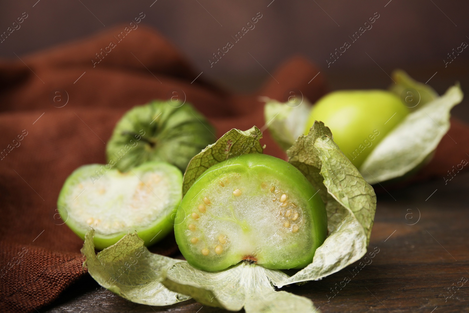 Photo of Fresh green tomatillos with husk on wooden table, closeup