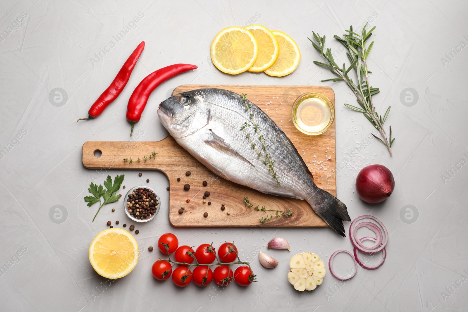 Photo of Flat lay composition with fresh raw dorado fish and ingredients on light grey table