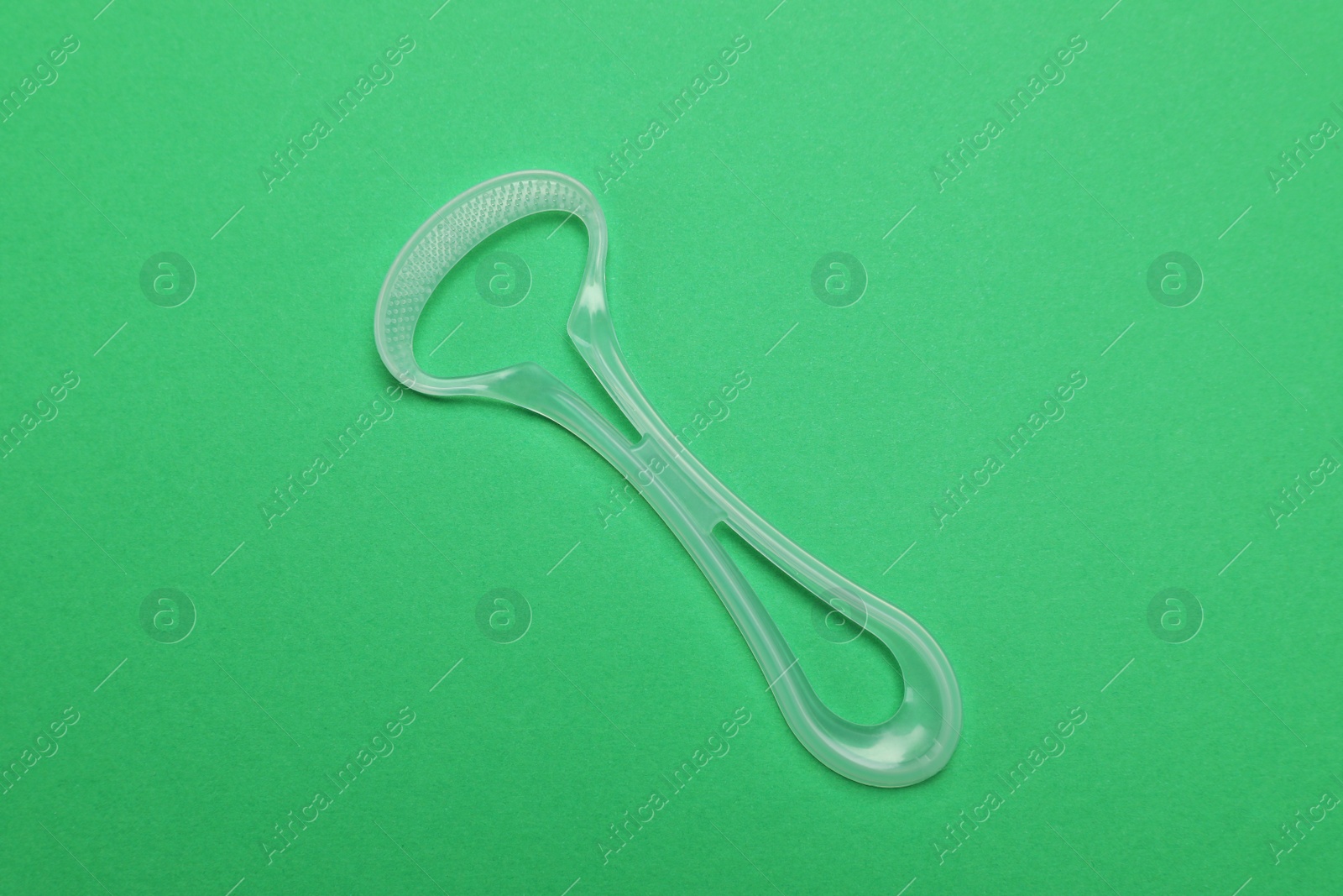 Photo of Transparent tongue cleaner on green background, top view