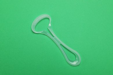 Photo of Transparent tongue cleaner on green background, top view