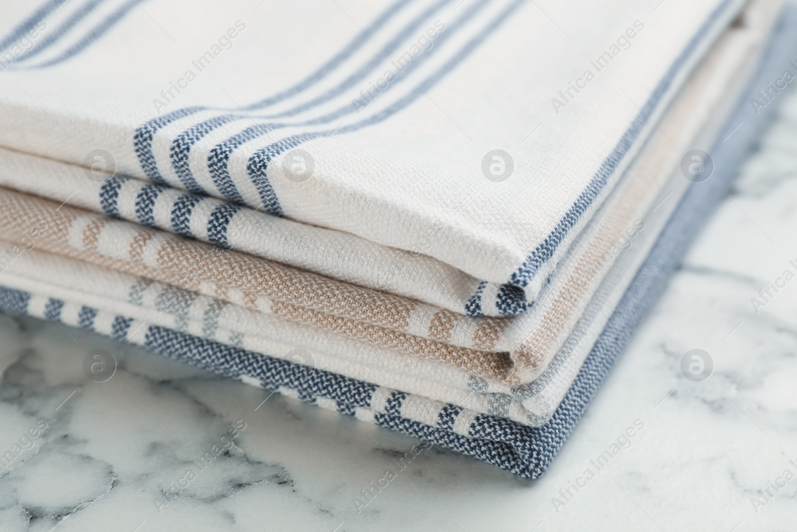 Photo of Stacked kitchen towels on white marble table, closeup