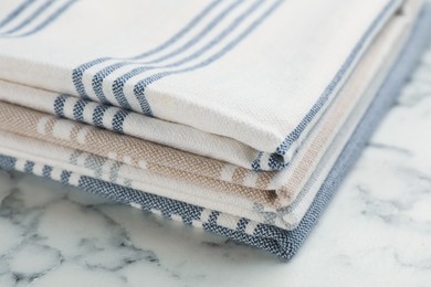 Stacked kitchen towels on white marble table, closeup