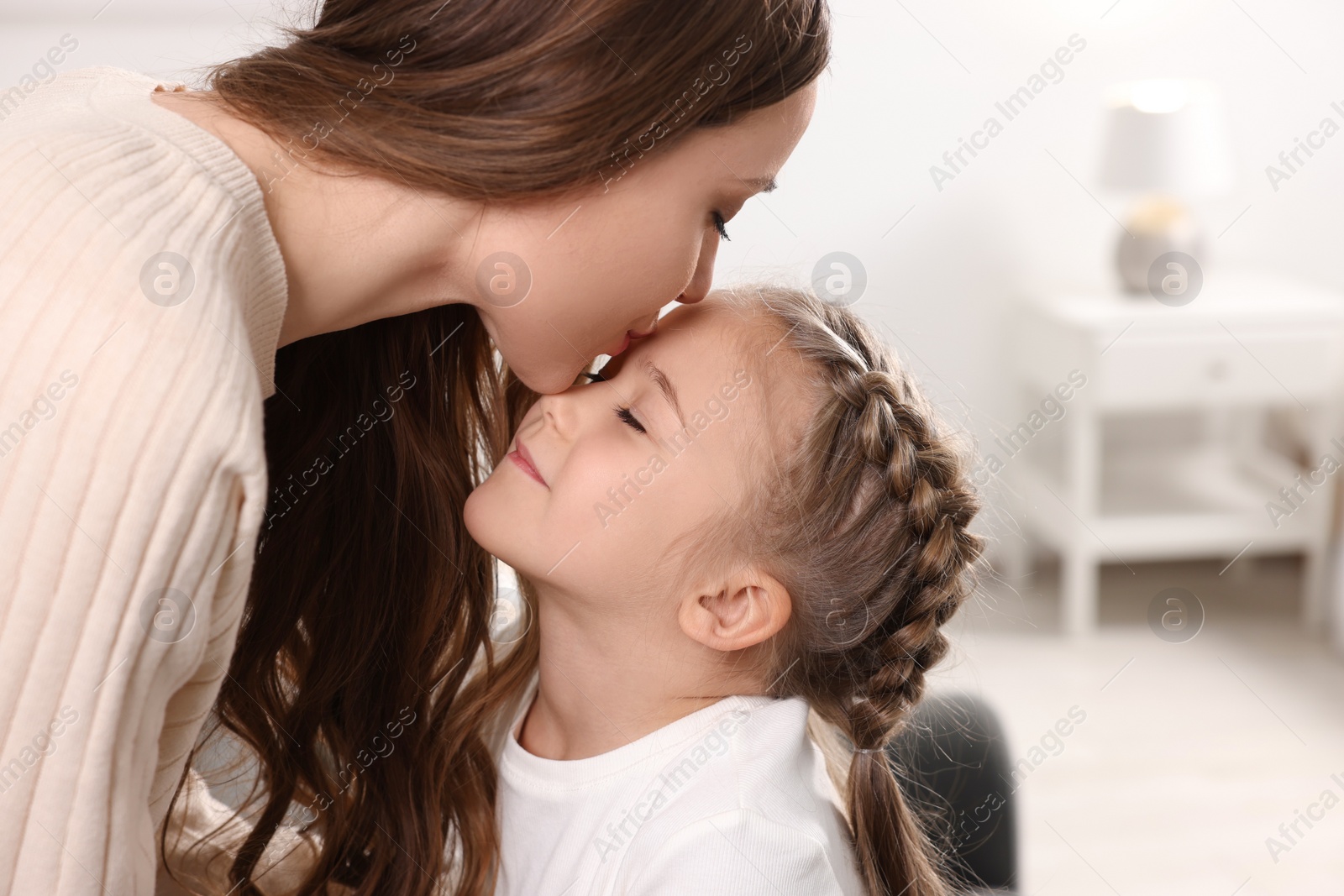 Photo of Happy mother kissing her cute daughter at home