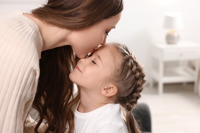 Photo of Happy mother kissing her cute daughter at home