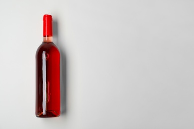 Photo of Bottle of expensive rose wine on light background, top view