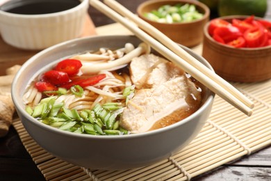 Photo of Delicious ramen with meat and ingredients on wooden table, closeup. Noodle soup