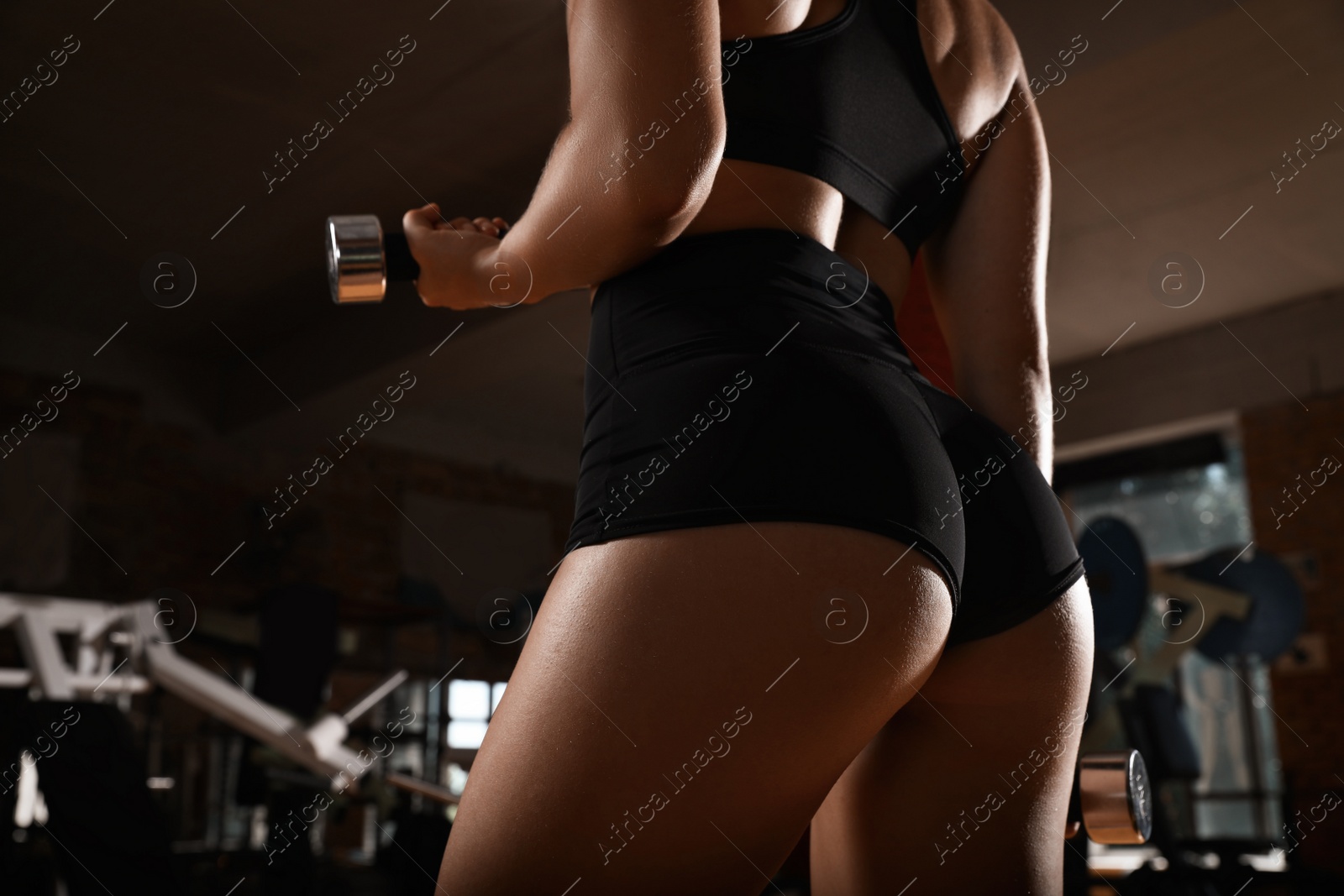 Photo of Woman with dumbbells training in modern gym, closeup