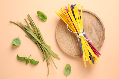 Flat lay composition with colorful tagliatelle on light orange background