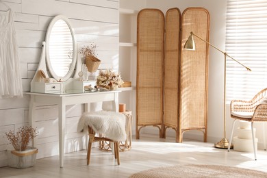 Wooden dressing table with decorative elements and makeup products in room. Interior design