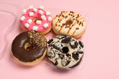 Photo of Box of delicious donuts on pink background, closeup