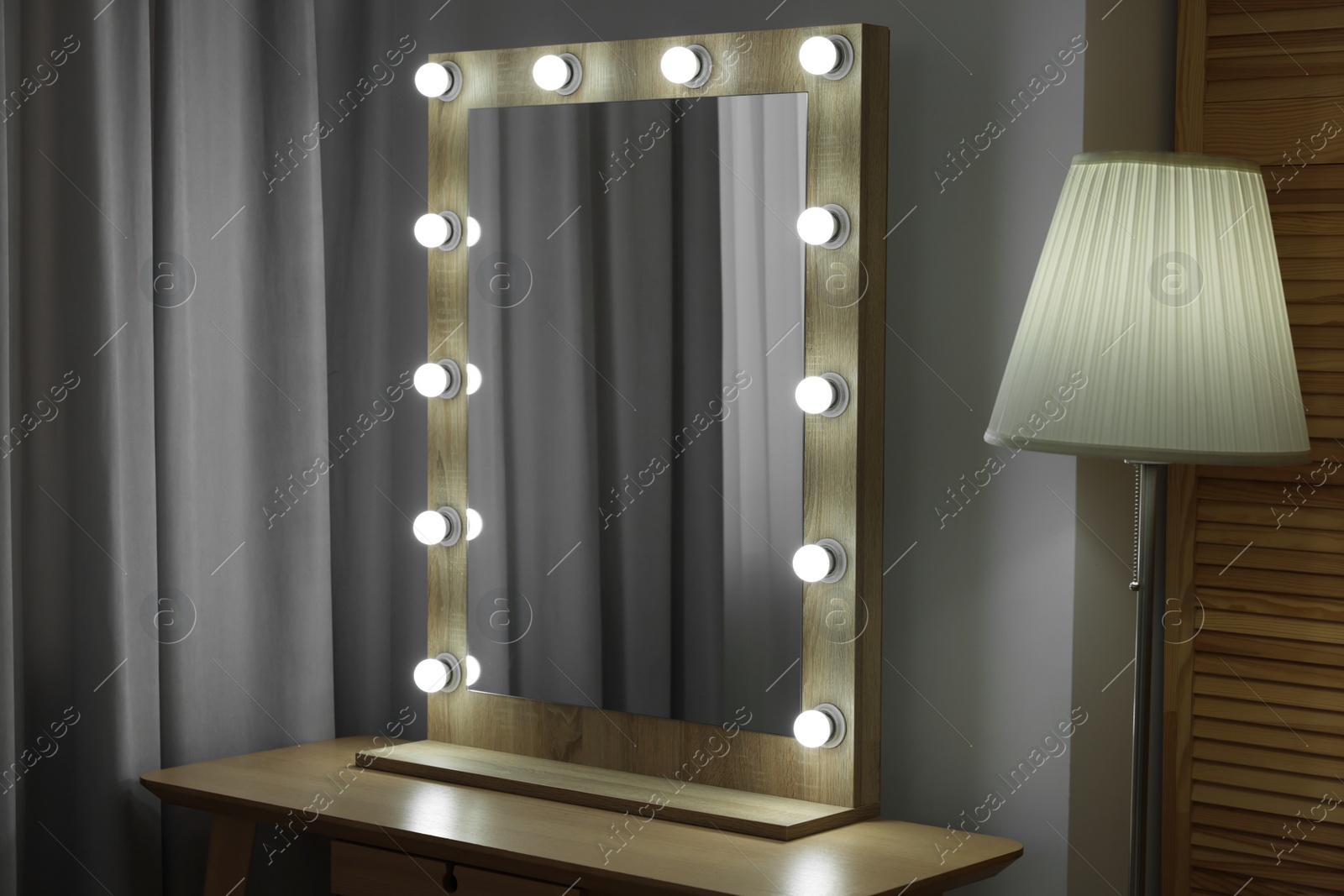 Photo of Beautiful mirror with light bulbs and lamp in makeup room