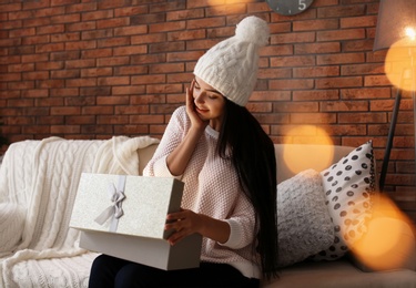 Photo of Beautiful young woman in hat opening gift box at home. Christmas celebration