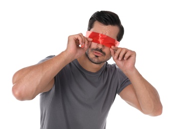 Young man wearing red blindfold on white background