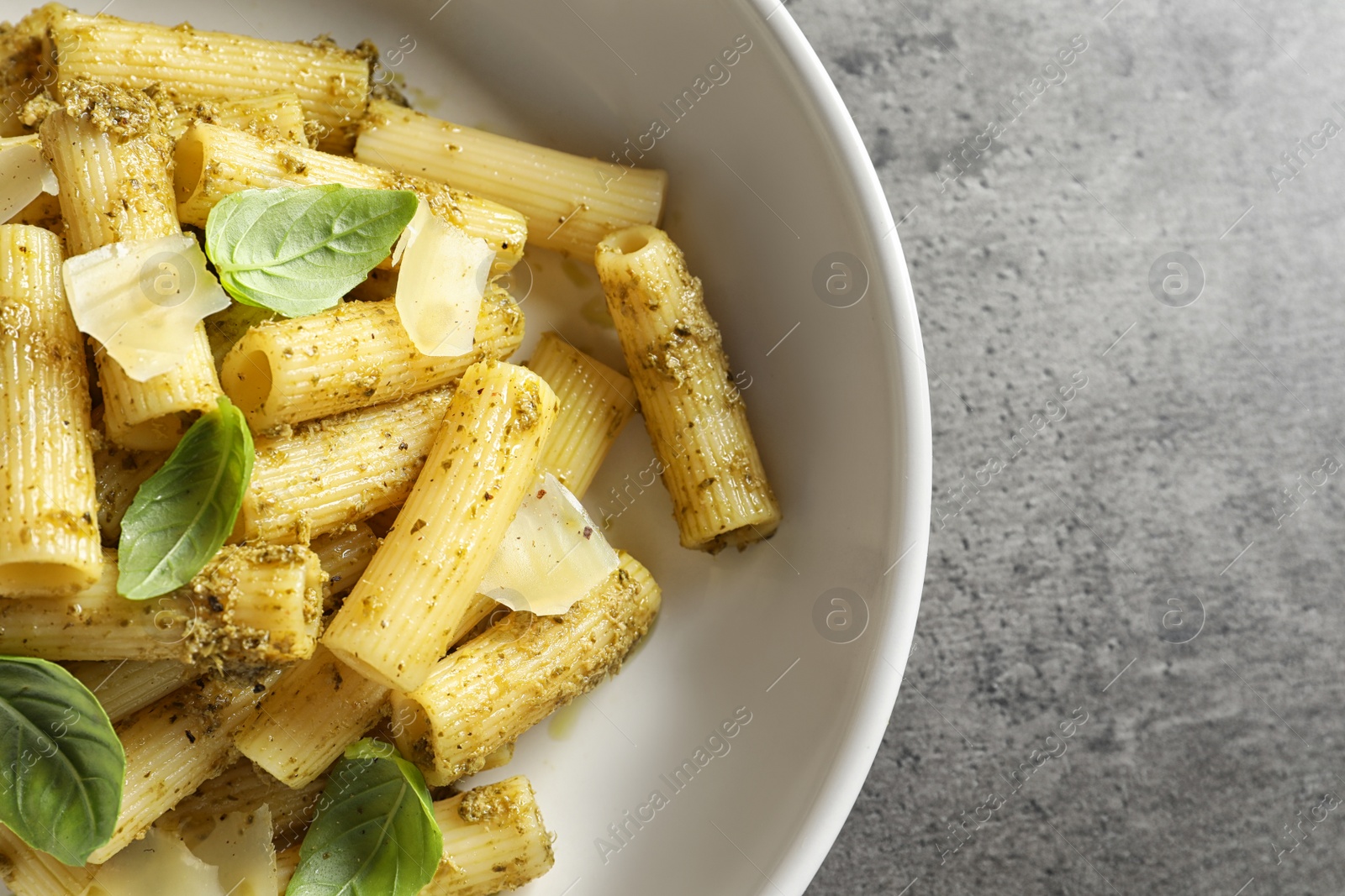Photo of Plate with delicious basil pesto pasta on gray table, top view