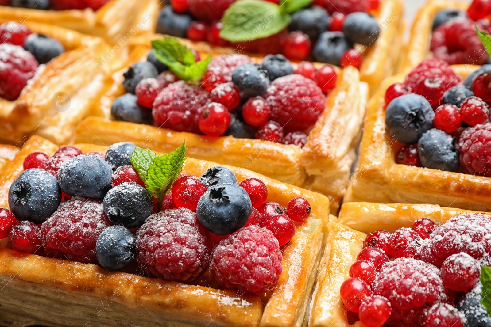 Photo of Fresh delicious puff pastry with sweet berries as background, closeup