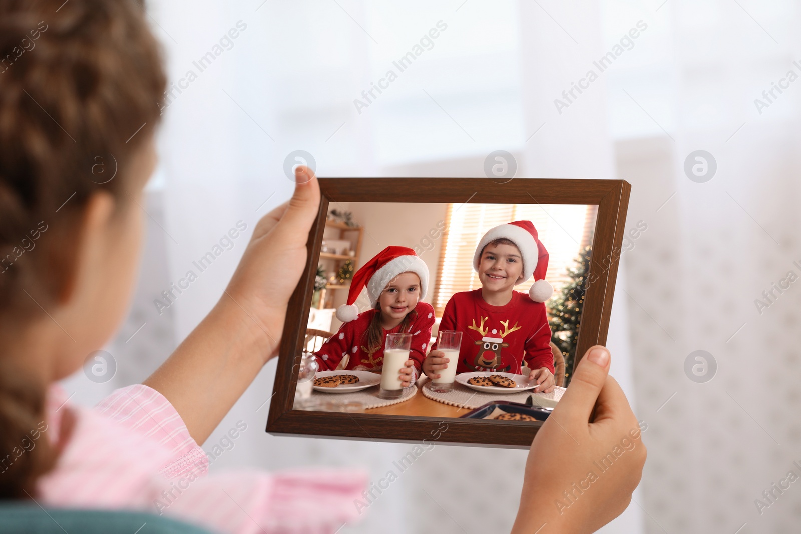 Image of Little girl holding frame with photo portrait of her family indoors, closeup