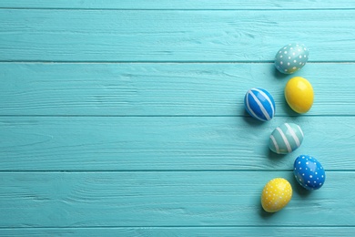 Flat lay composition of painted Easter eggs on wooden table, space for text