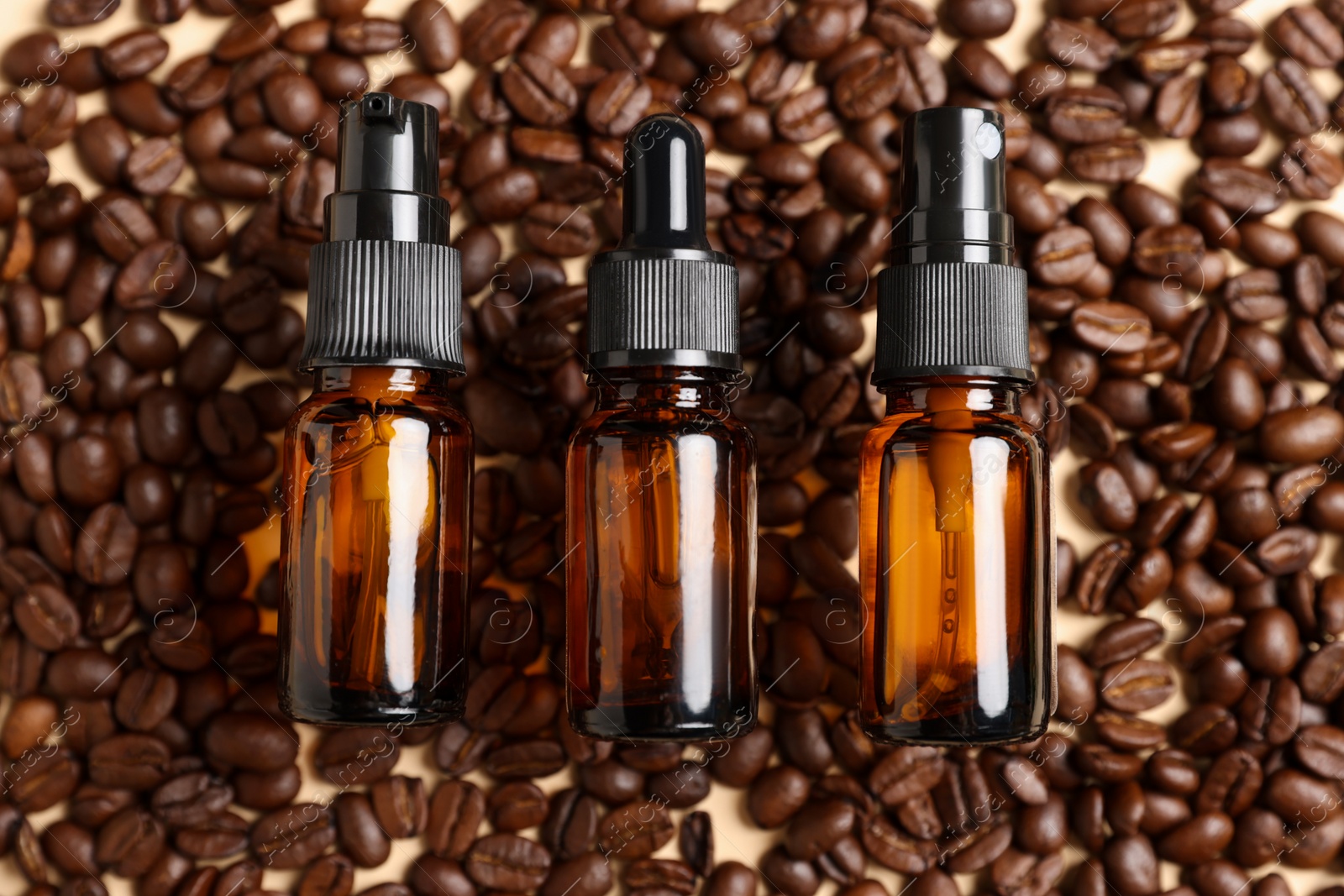 Photo of Bottles of organic cosmetic products and coffee beans on beige background, flat lay