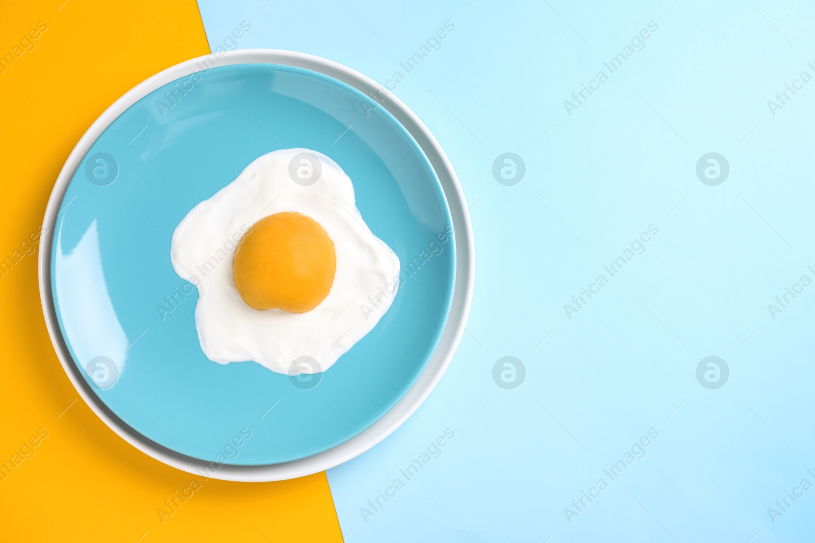 Photo of Tasty yogurt with peach imitating fried egg on color background, top view