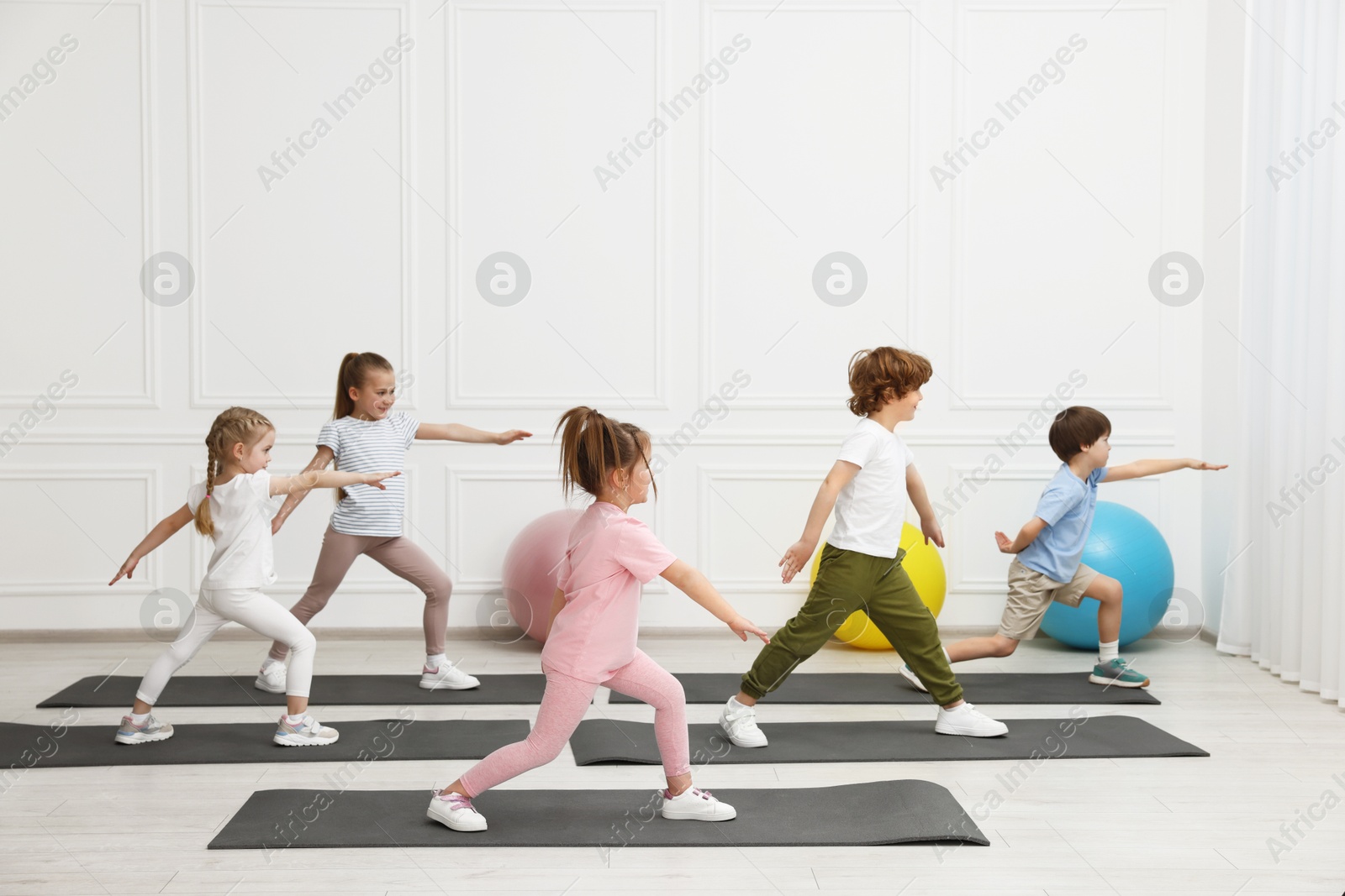 Photo of Group of children doing gymnastic exercises on mats indoors